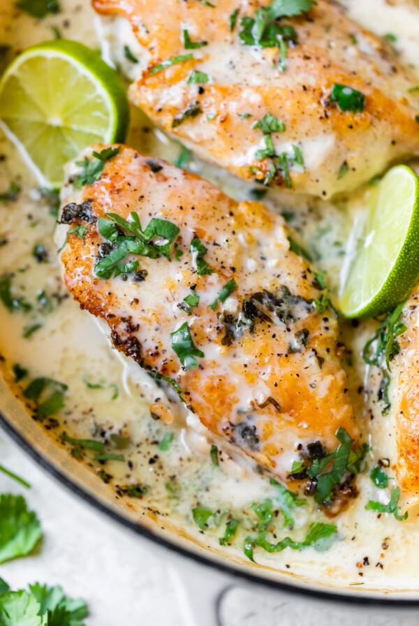 chicken in a skillet with lime wedges