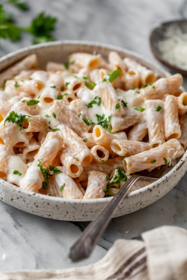 cottage cheese alfredo sauce added on top of cooked pasta in a bowl with a fork