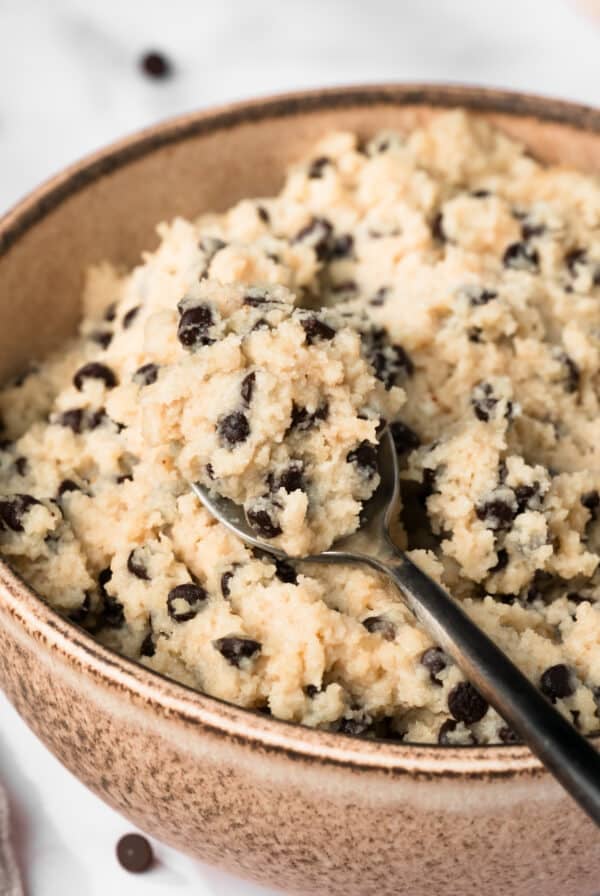 close up on a spoonful of chocolate chip cottage cheese cookie dough in a bowl.