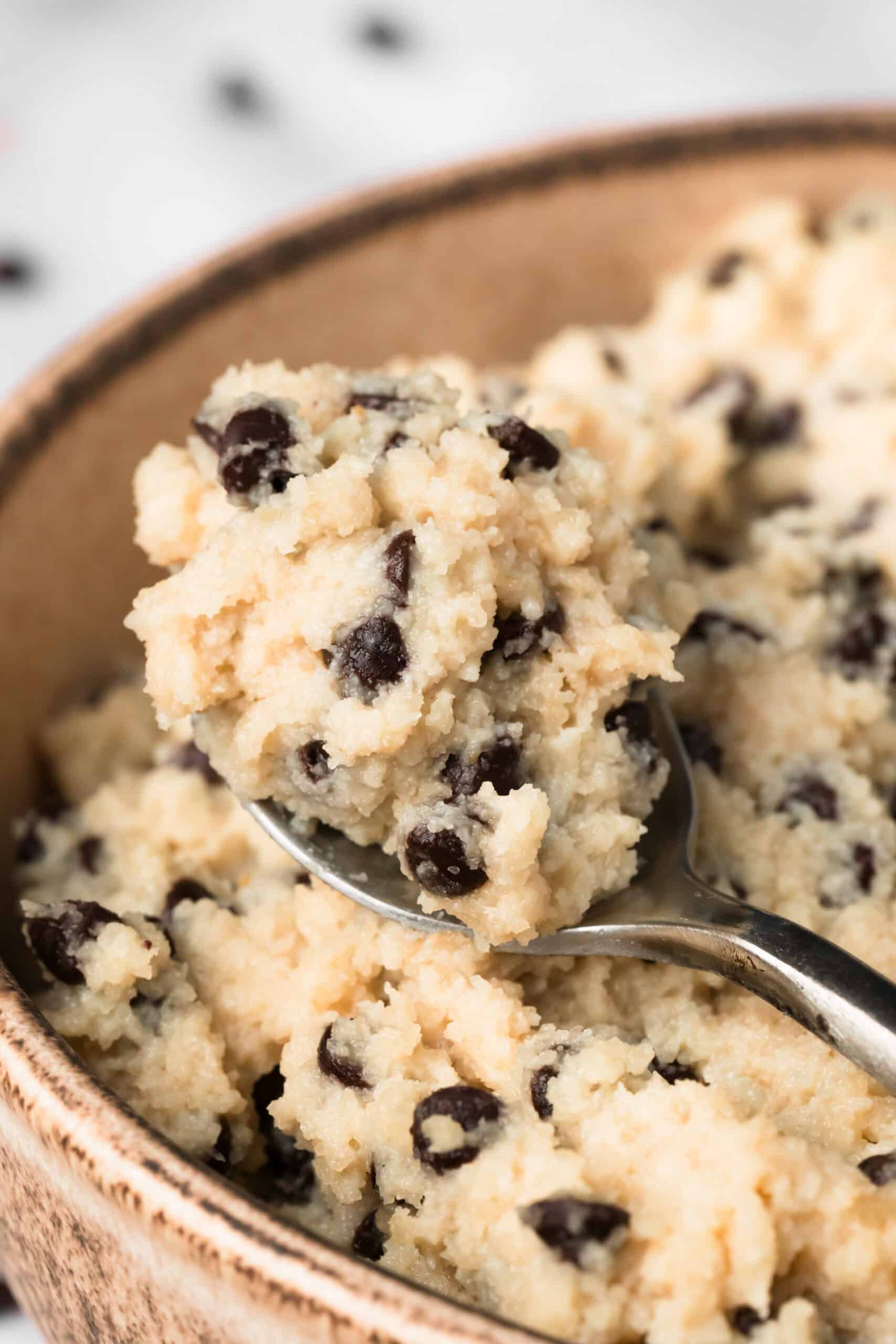 close up on a spoonful of chocolate chip cottage cheese cookie dough in a bowl.