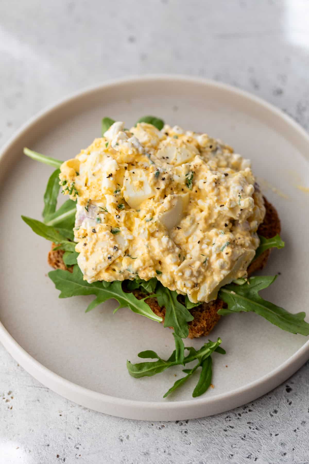 cottage cheese egg salad on a piece of toast with arugula.