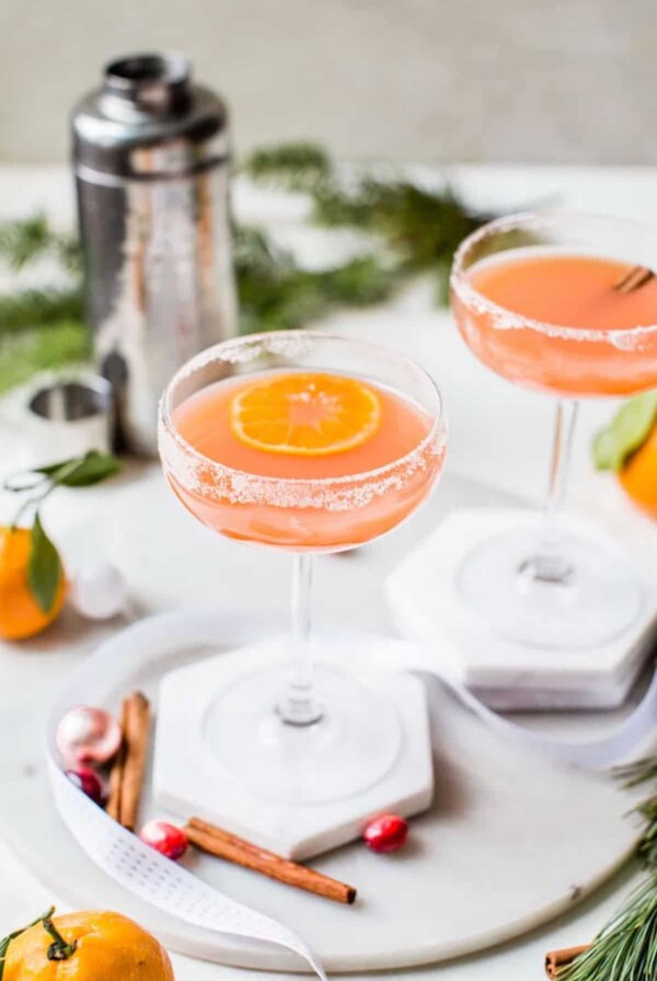 a cocktail on a glass with a cocktail shaker behind it
