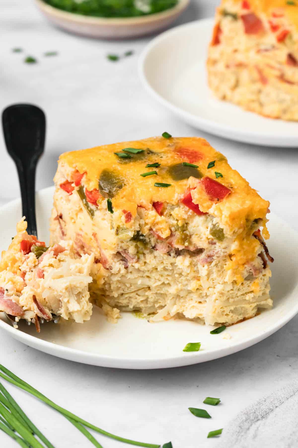 side view of a fork cutting into a slice of crockpot breakfast casserole on a plate.