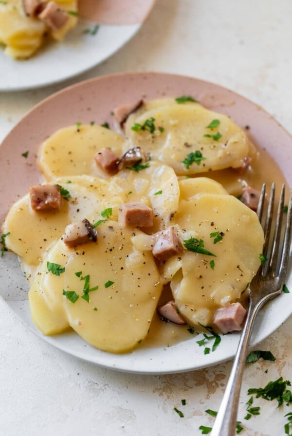 scalloped potatoes and ham on a plate with a fork
