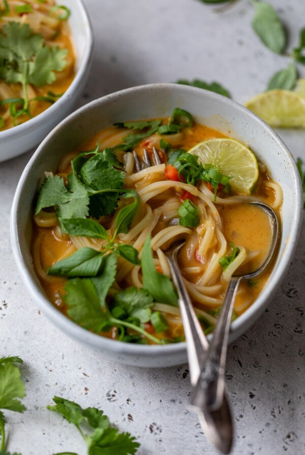 curry noodle soup in a bowl with a fork and spoon