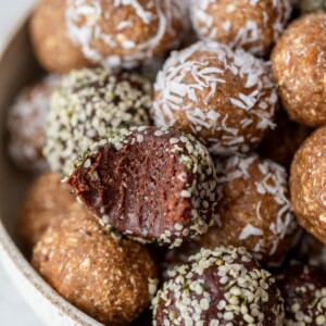 date energy balls in a bowl with a bite taken out of one