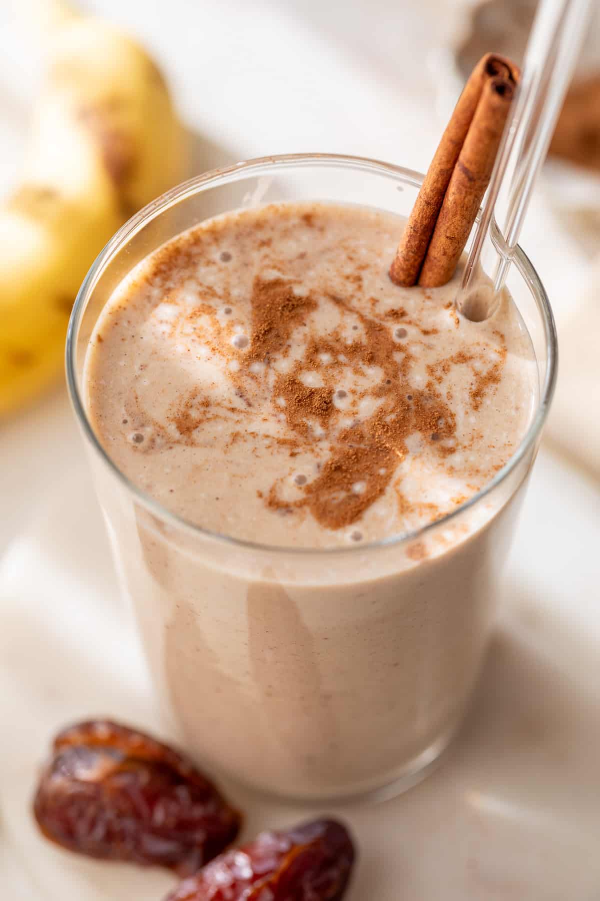 date smoothie in a glass with a straw and cinnamon stick