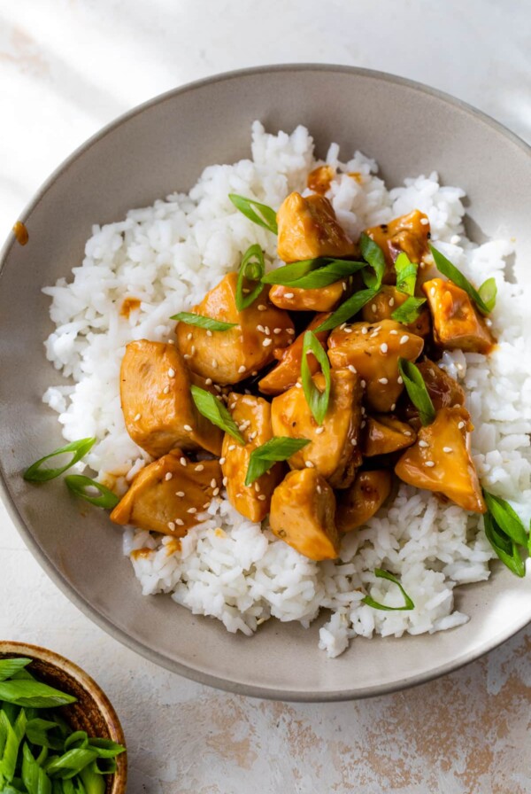 orange chicken on top of rice in a bowl