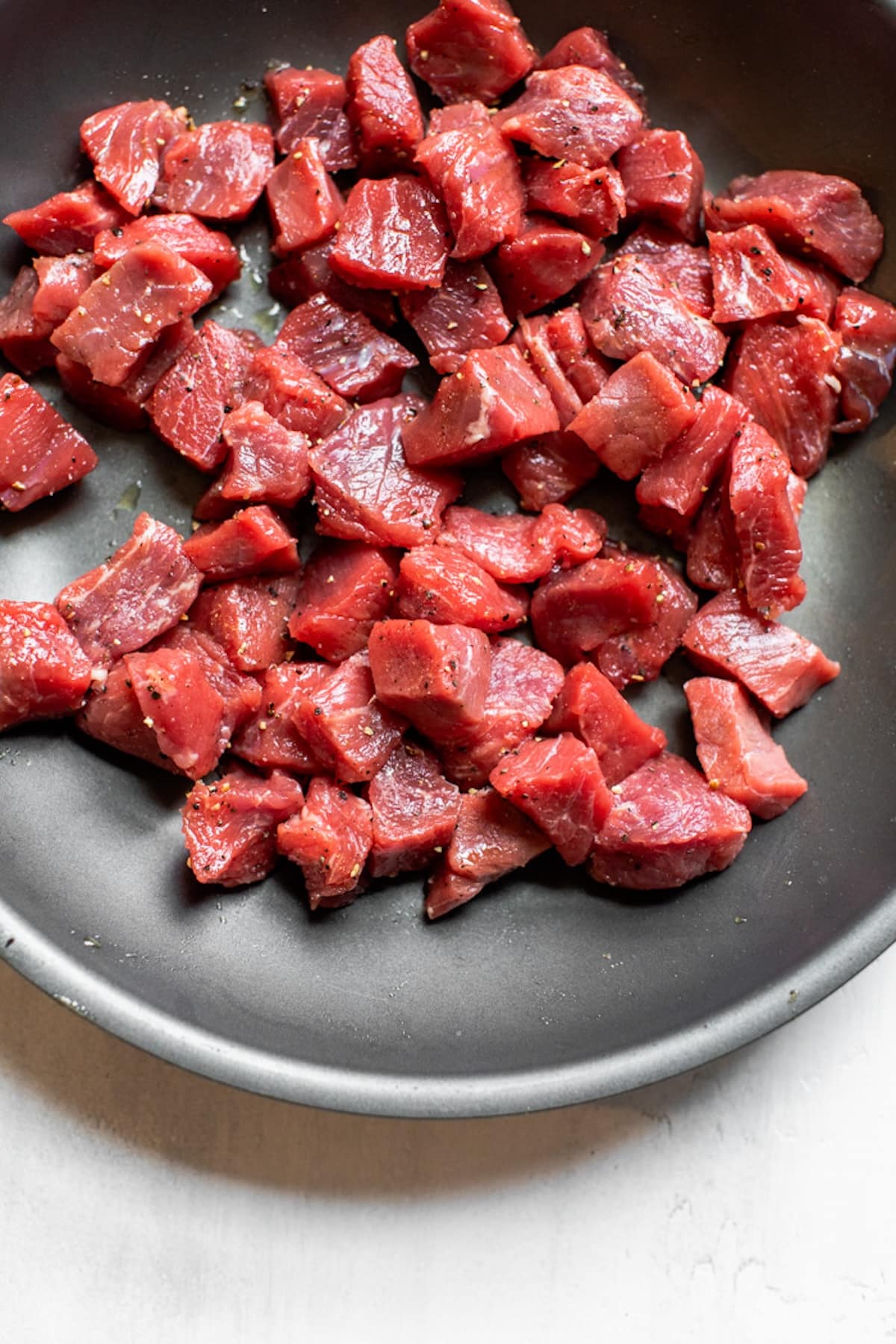 raw steak cut into bite-size pieces in a skillet