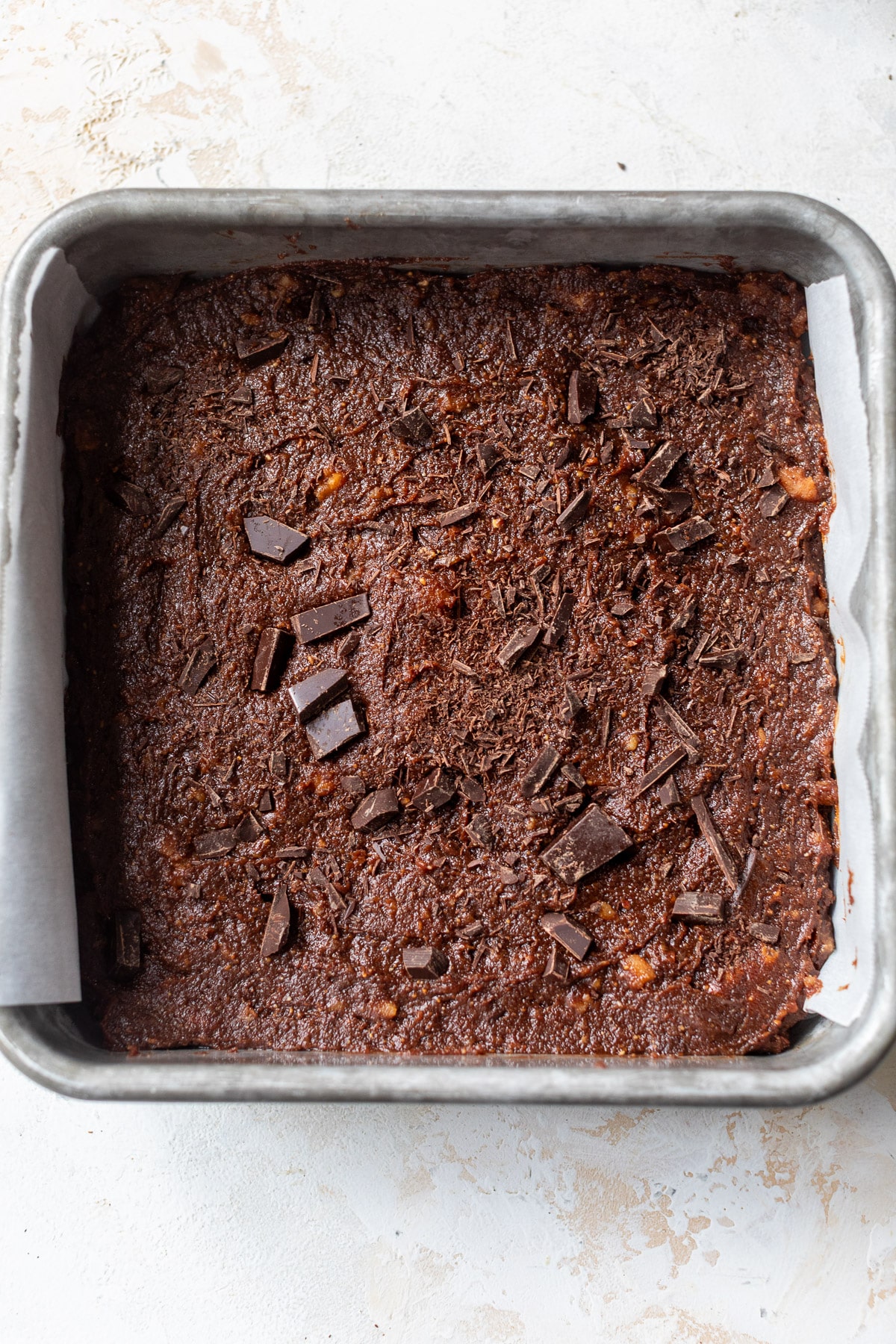 brownie batter in a square baking dish with parchment paper