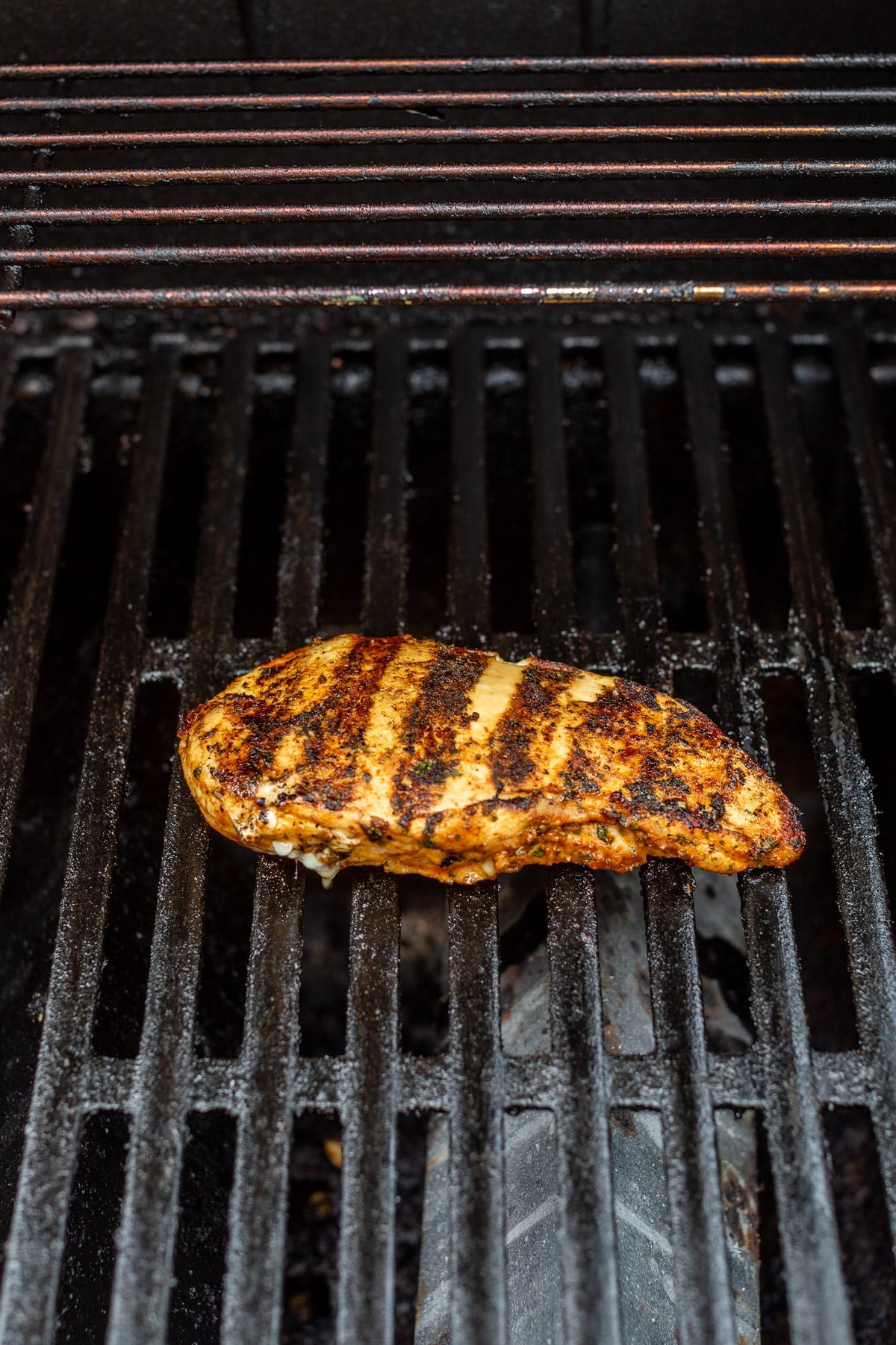 a chicken breast with grill marks on an outdoor grill.