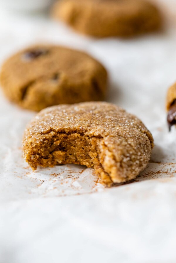 pumpkin cookie on parchment paper with a bite taken out of it