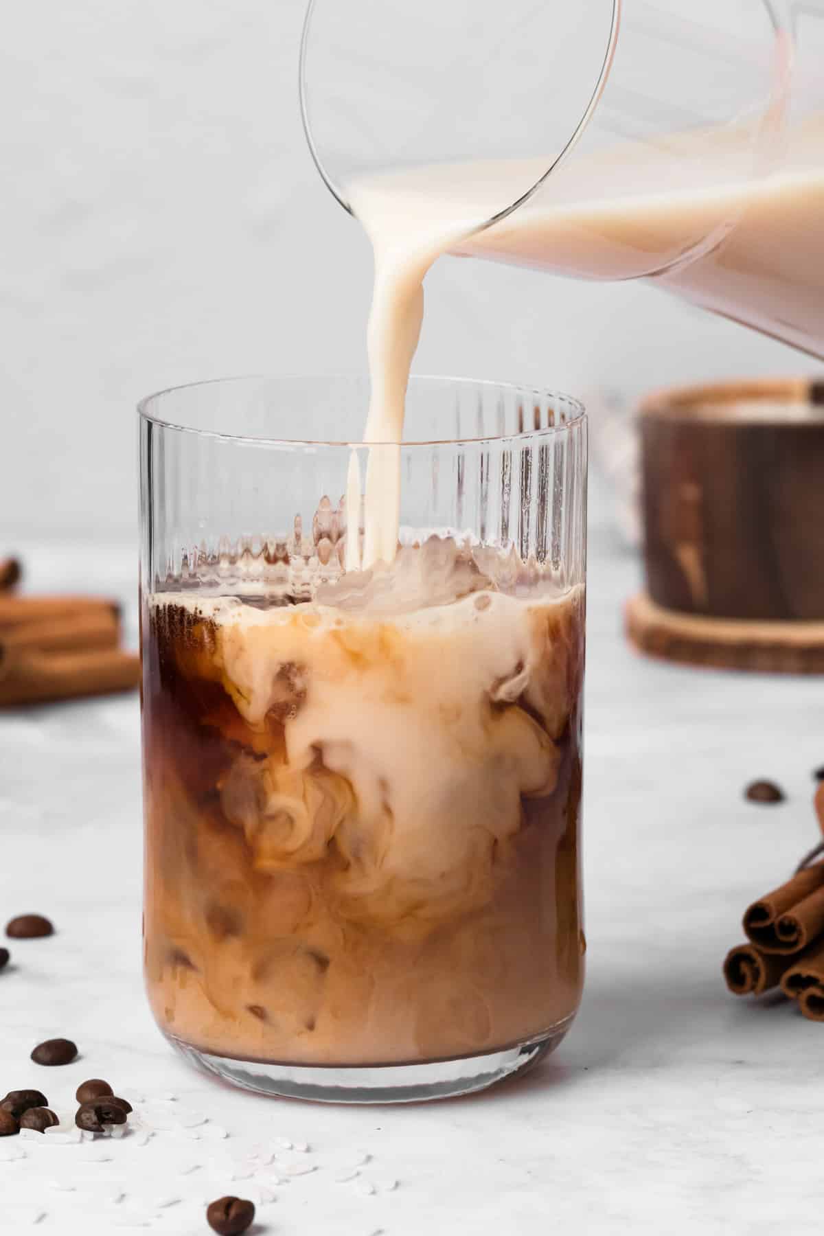 side view of pouring horchata into a glass of espresso.