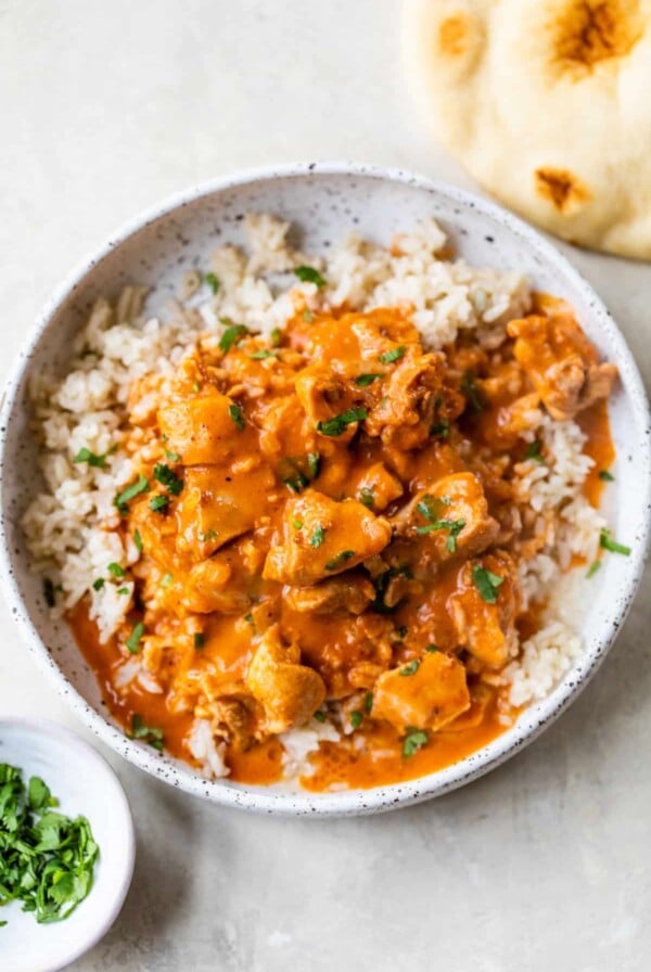 a bowl of butter chicken overtop rice in a bowl