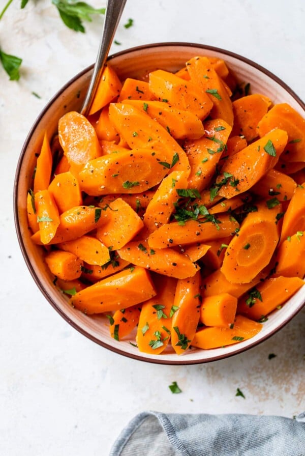 instant pot carrots inside a bowl with a fork and fresh parsley on top