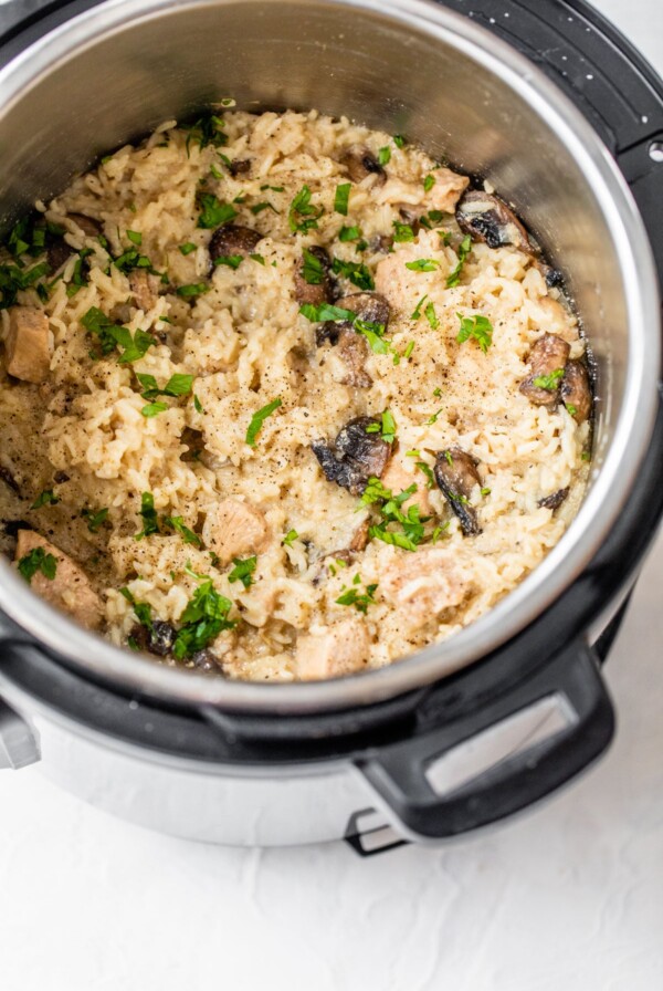 pressure cooker with rice, chicken, mushrooms, and fresh parsley