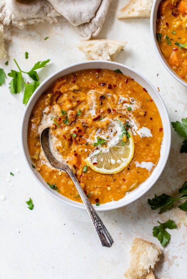 a bowl of red lentil soup topped with a lemon wedge