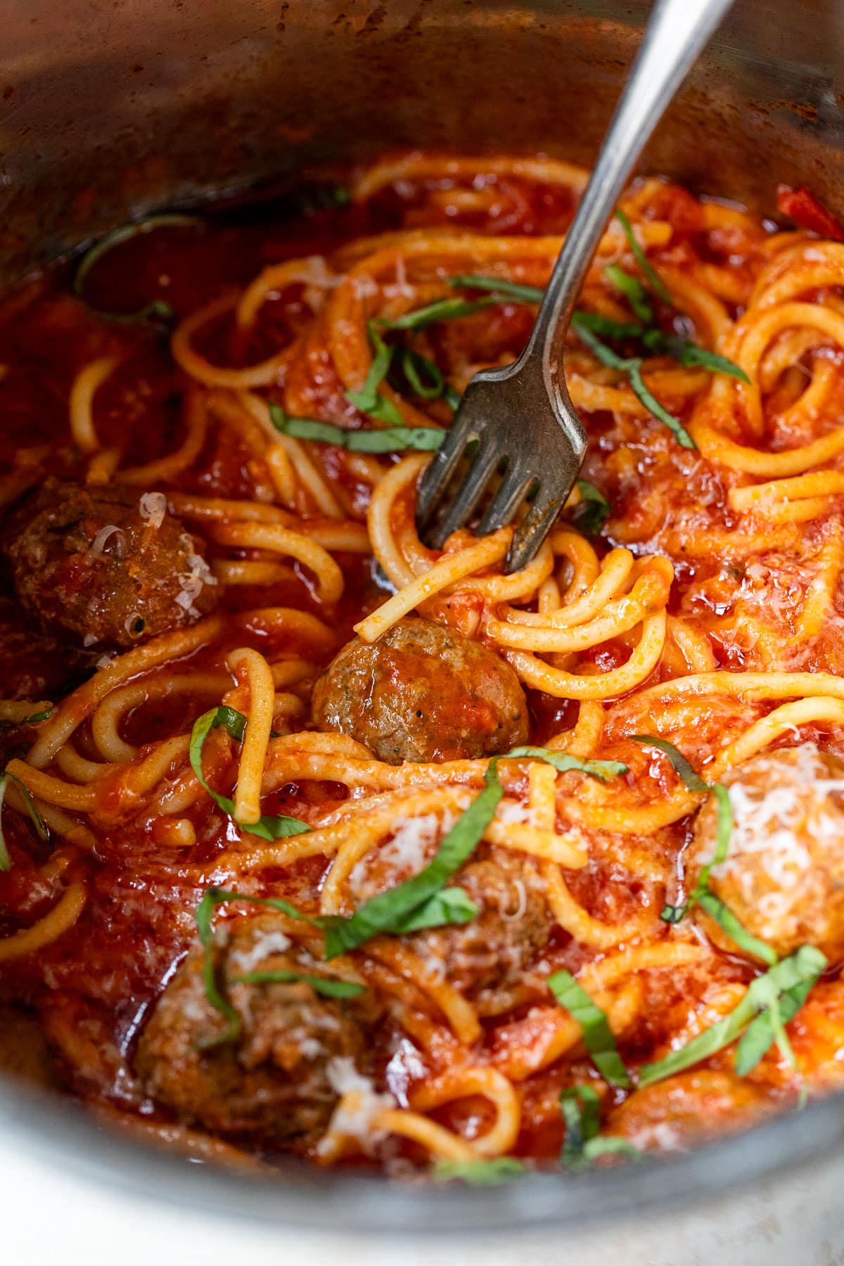 close up on a fork in a batch of spaghetti and meatballs in an instant pot.