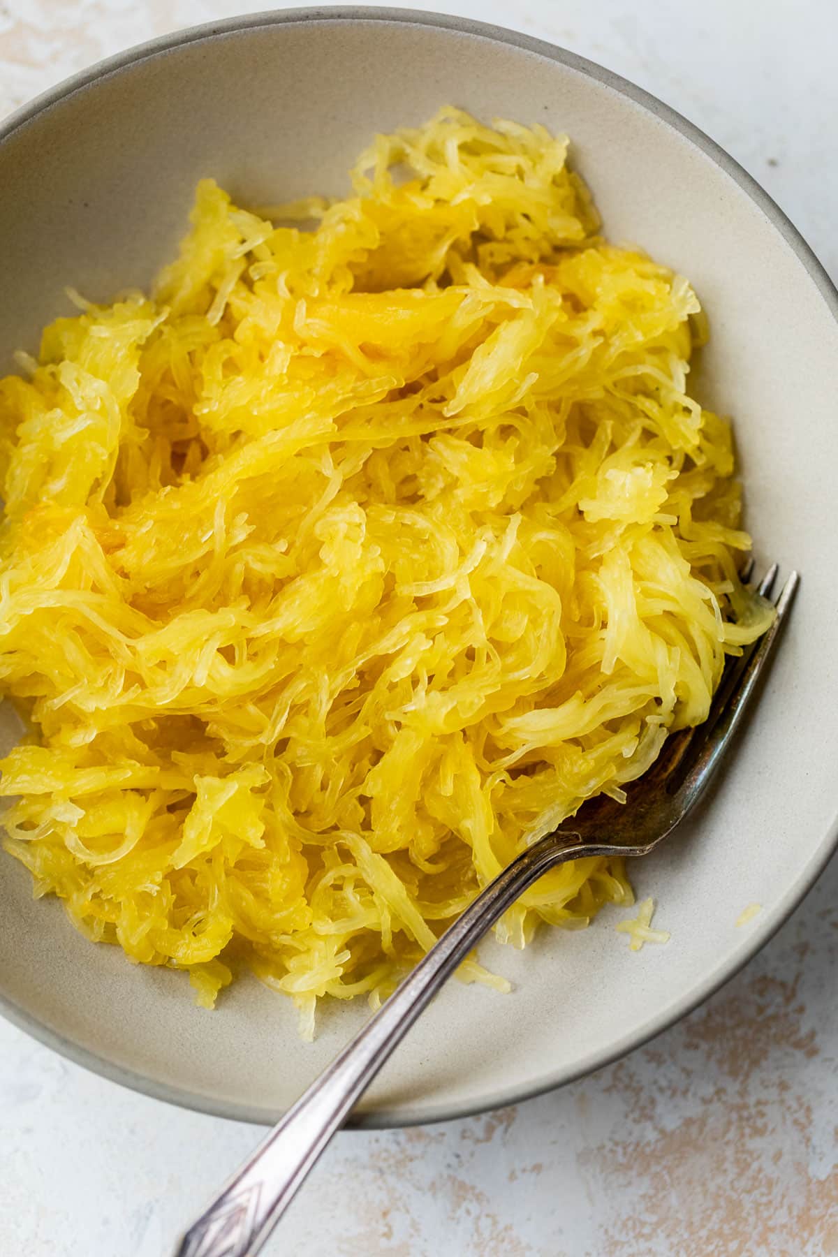 overhead view of cooked spaghetti squash stands in a bowl with a fork.