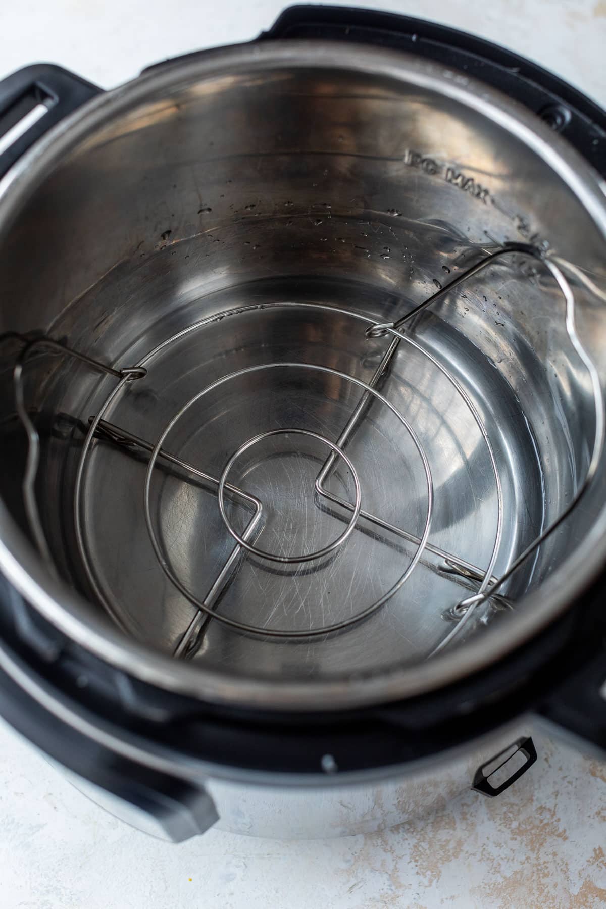 overhead view of an instant pot with some water and a trivet on the bottom.