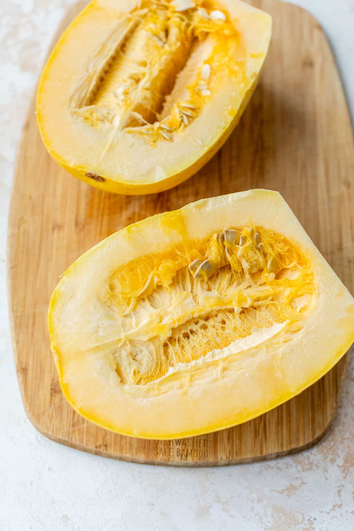 overhead view of a sliced spaghetti squash on a bamboo cutting board.