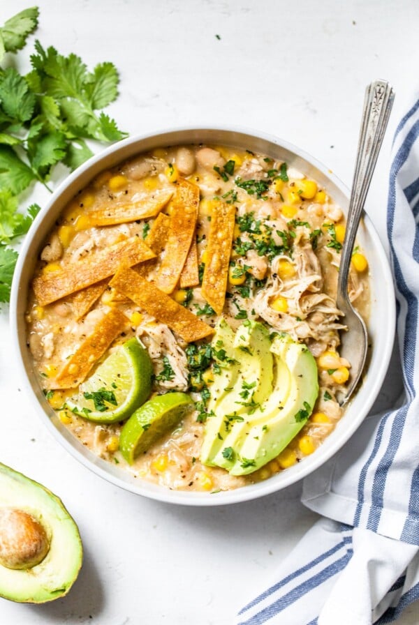 bowl of soup topped with avocado, cilantro and tortilla strips