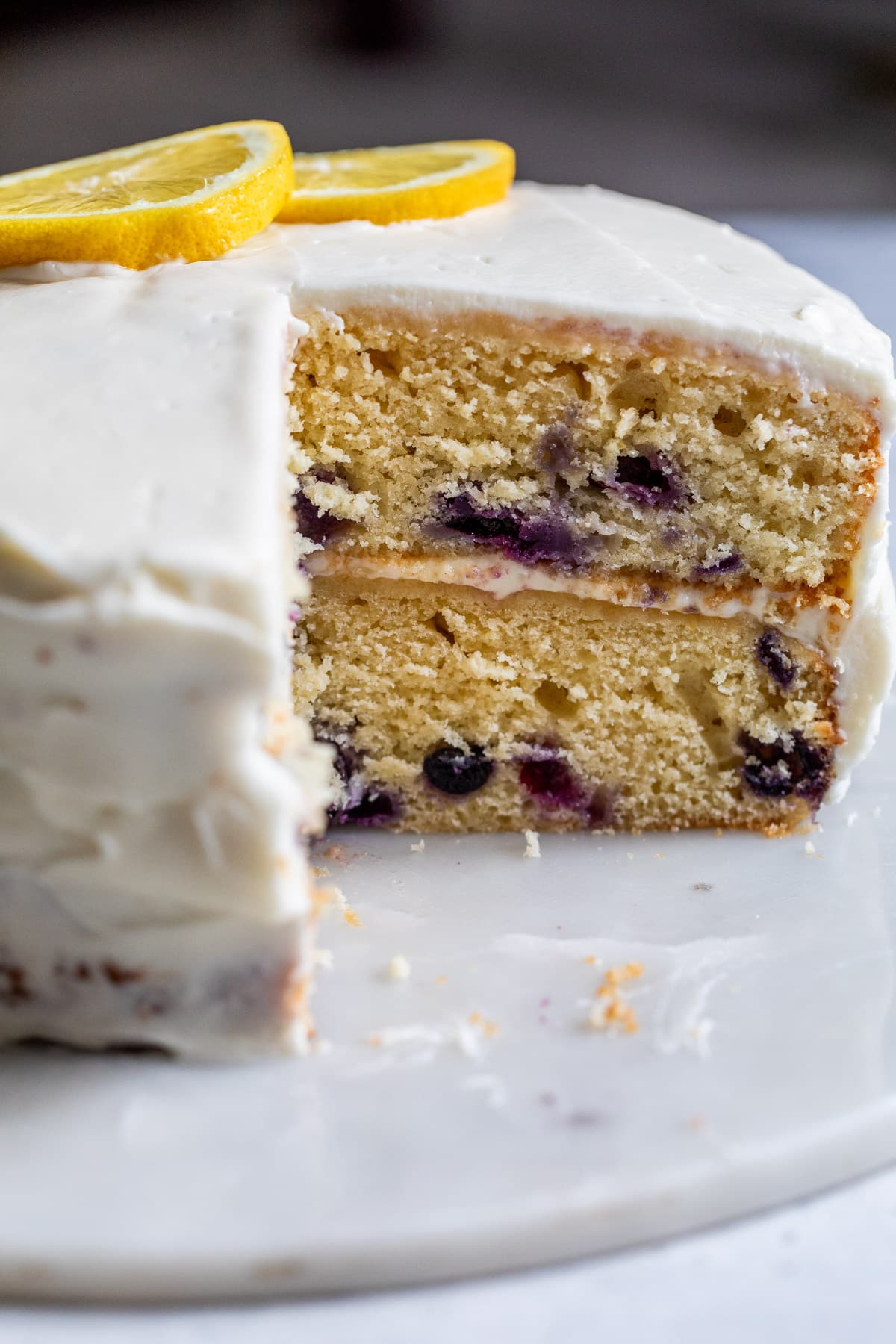 a two-layer lemon blueberry cake with a slice removed.