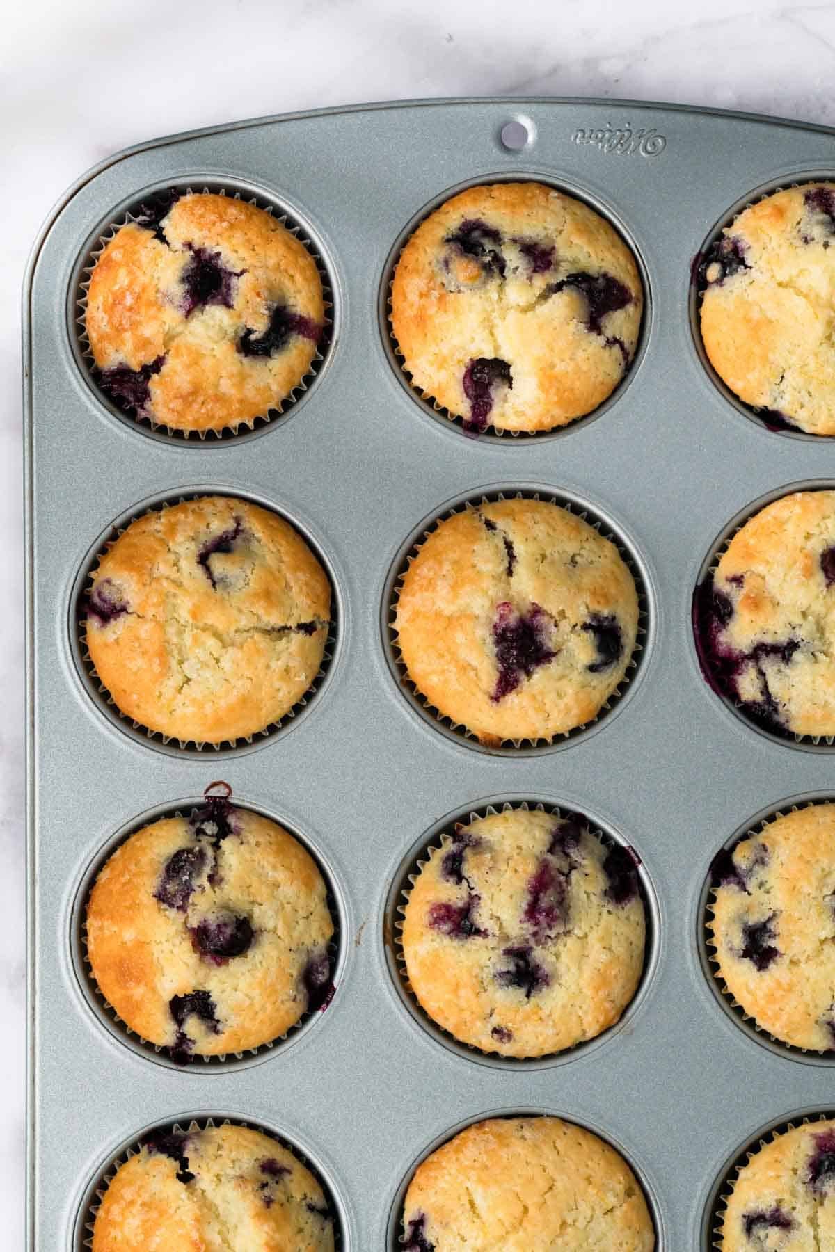 overhead view of baked lemon blueberry muffins in a muffin tin.