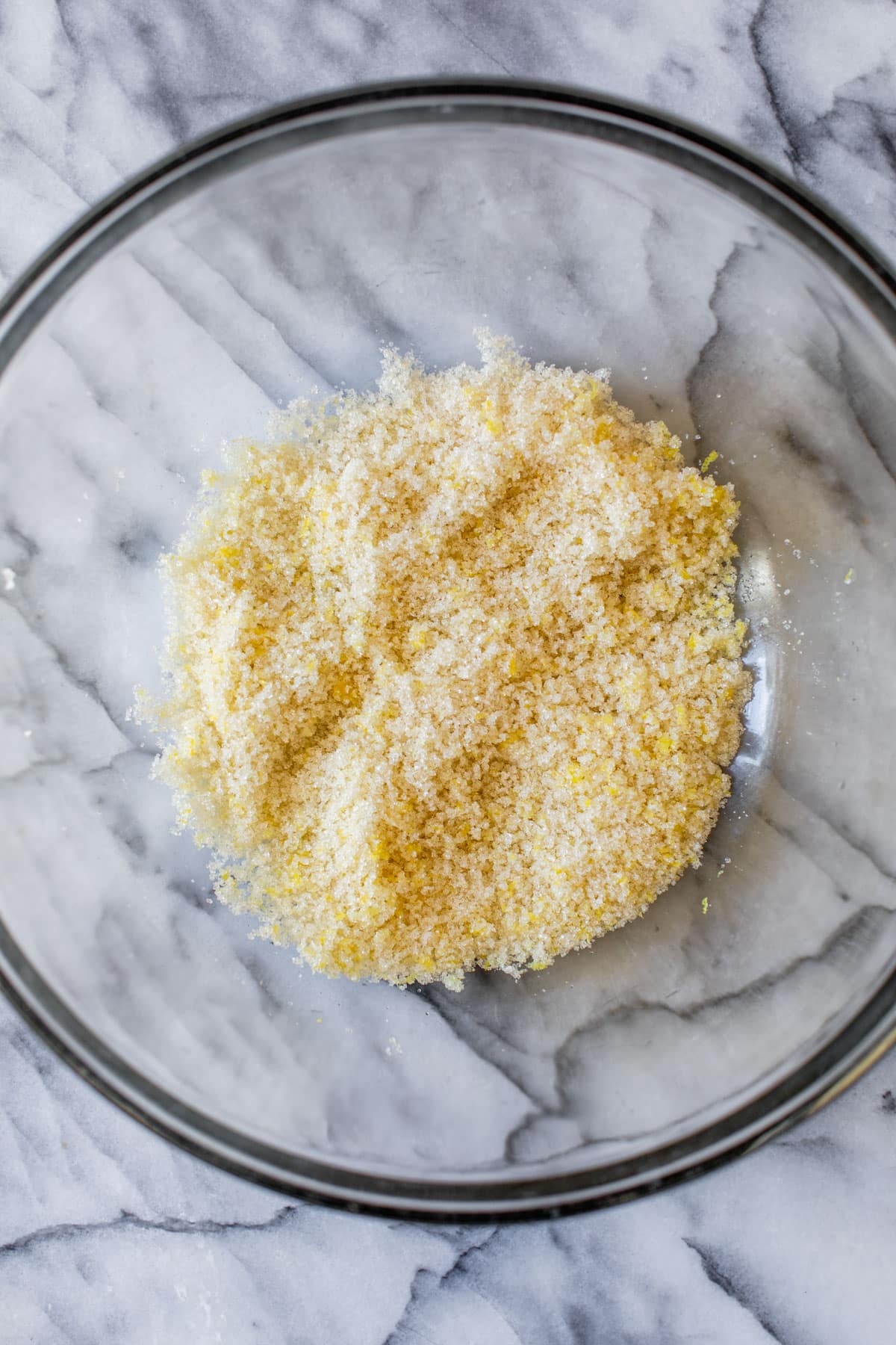 sugar and lemon zest mixed together in a glass bowl