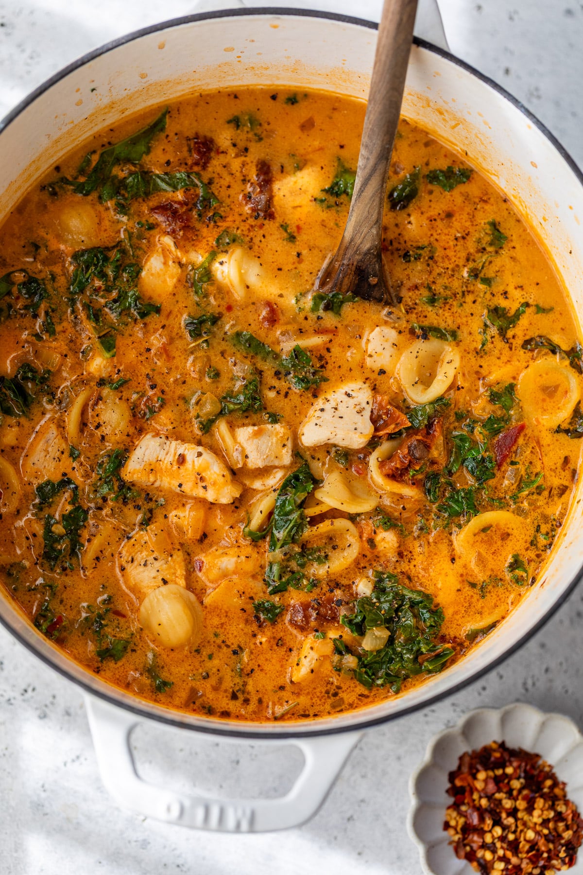 using a wooden spoon to stir Marry Me Chicken Soup in a large pot.
