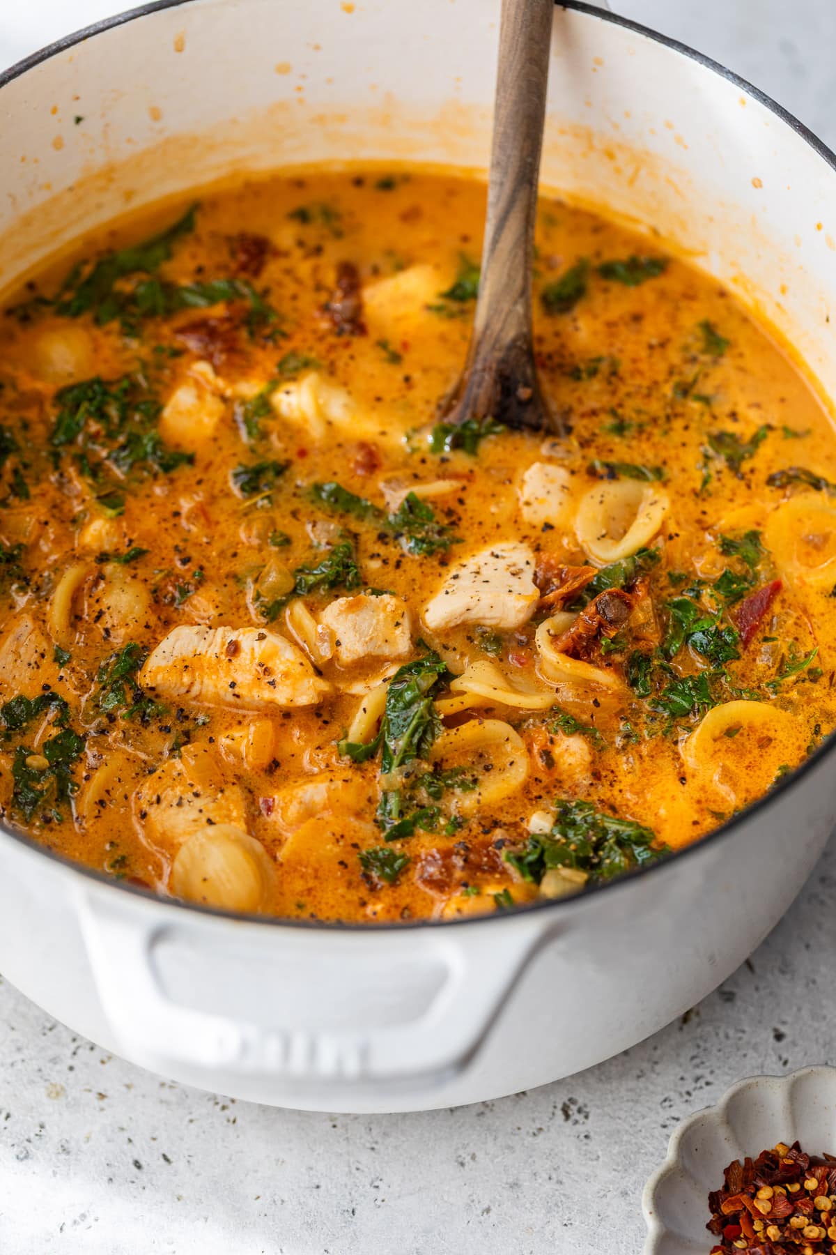 using a wooden spoon to stir Marry Me Chicken Soup in a large pot.