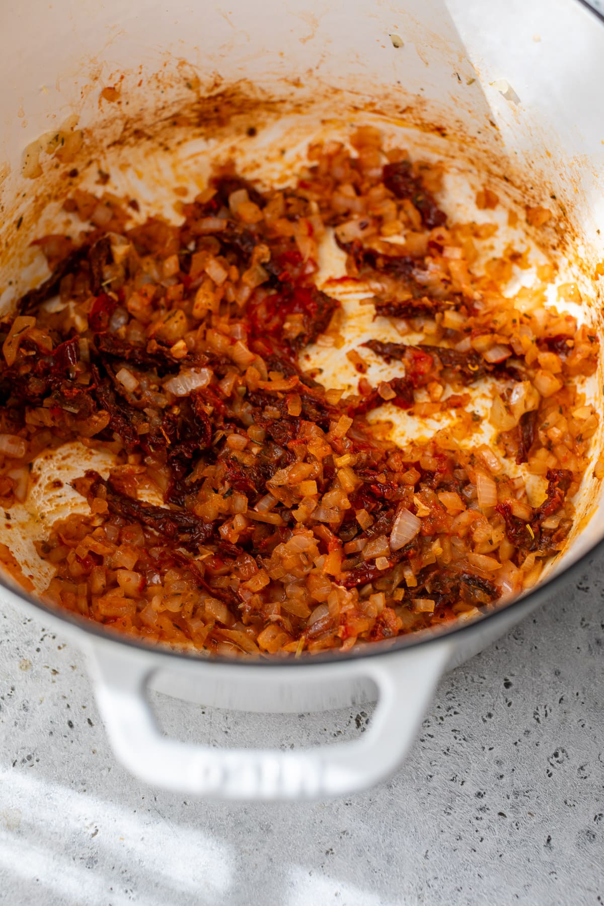 sauteeing chopped onions and tomato paste in a large pot for Marry Me Chicken Soup.