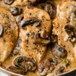 close up photo of cooked chicken breast in a skillet with a creamy mushroom sauce