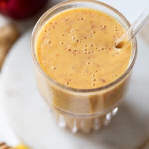 close up on a tall glass filled with an orange Nectarine Smoothie.