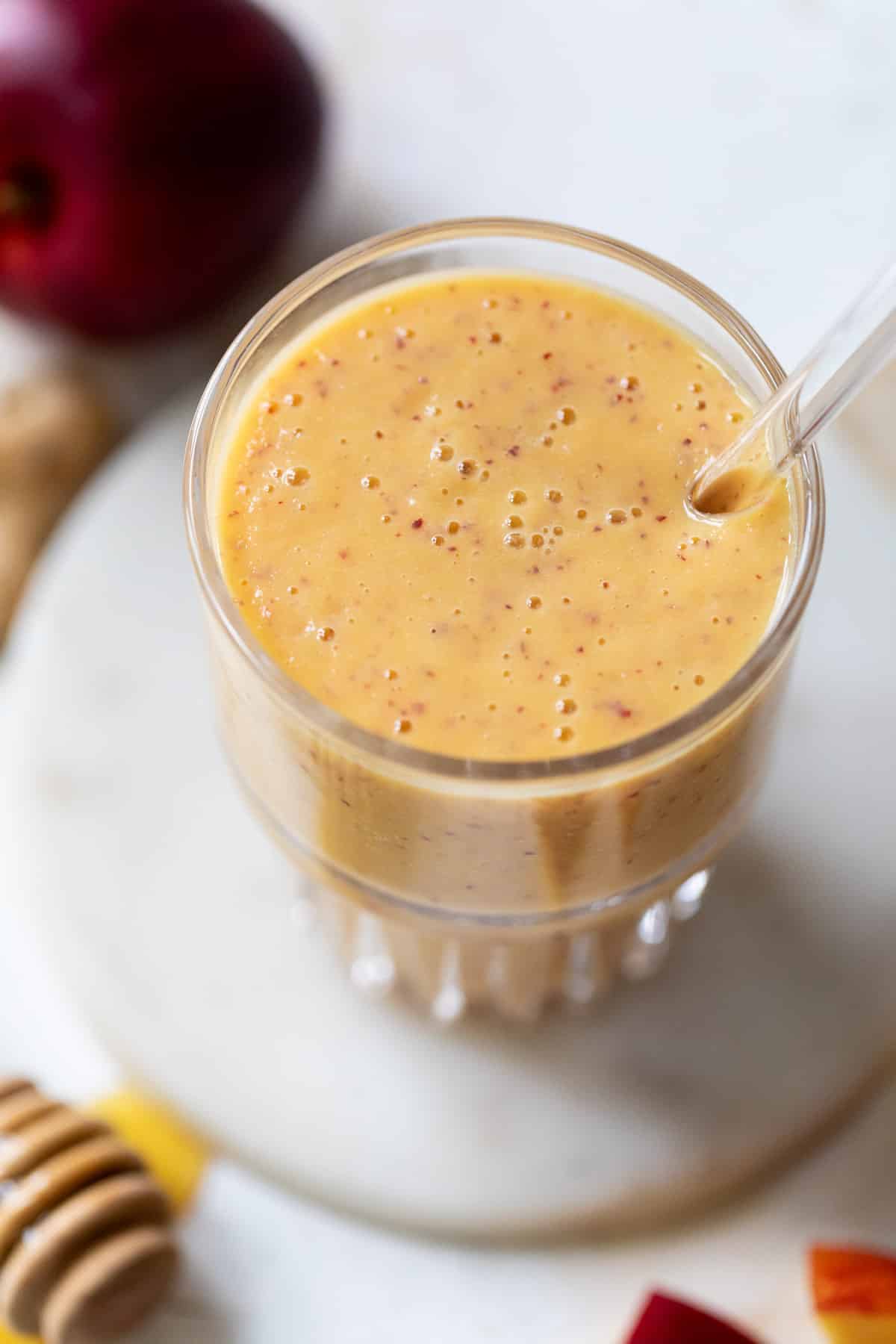 close up on a tall glass filled with an orange Nectarine Smoothie.