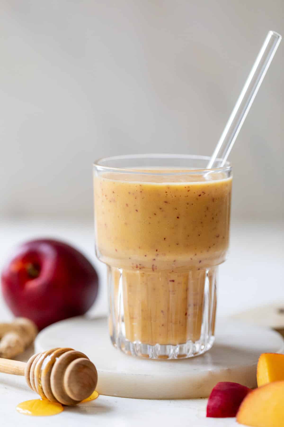 close up on a tall glass filled with an orange Nectarine Smoothie.