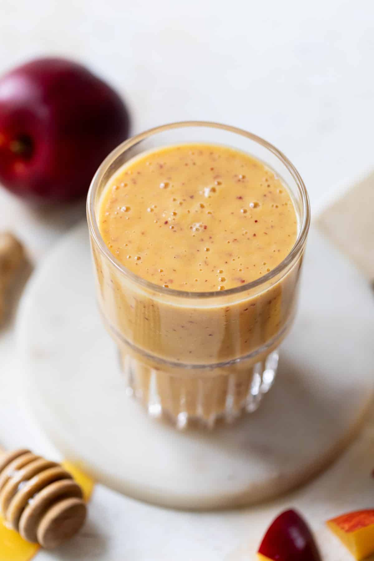 close up on a tall glass filled with an orange Nectarine Smoothie.
