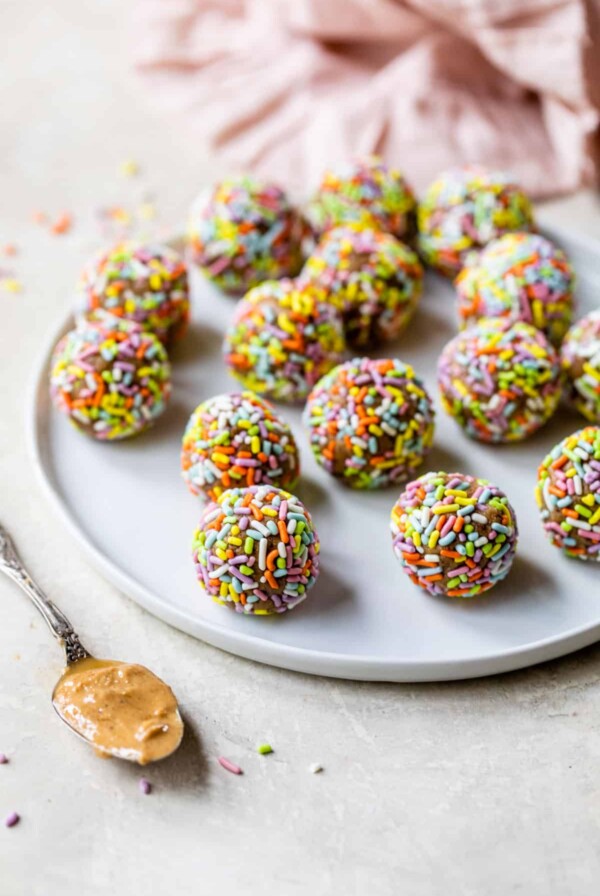 a plate filled with energy balls covered in rainbow sprinkles
