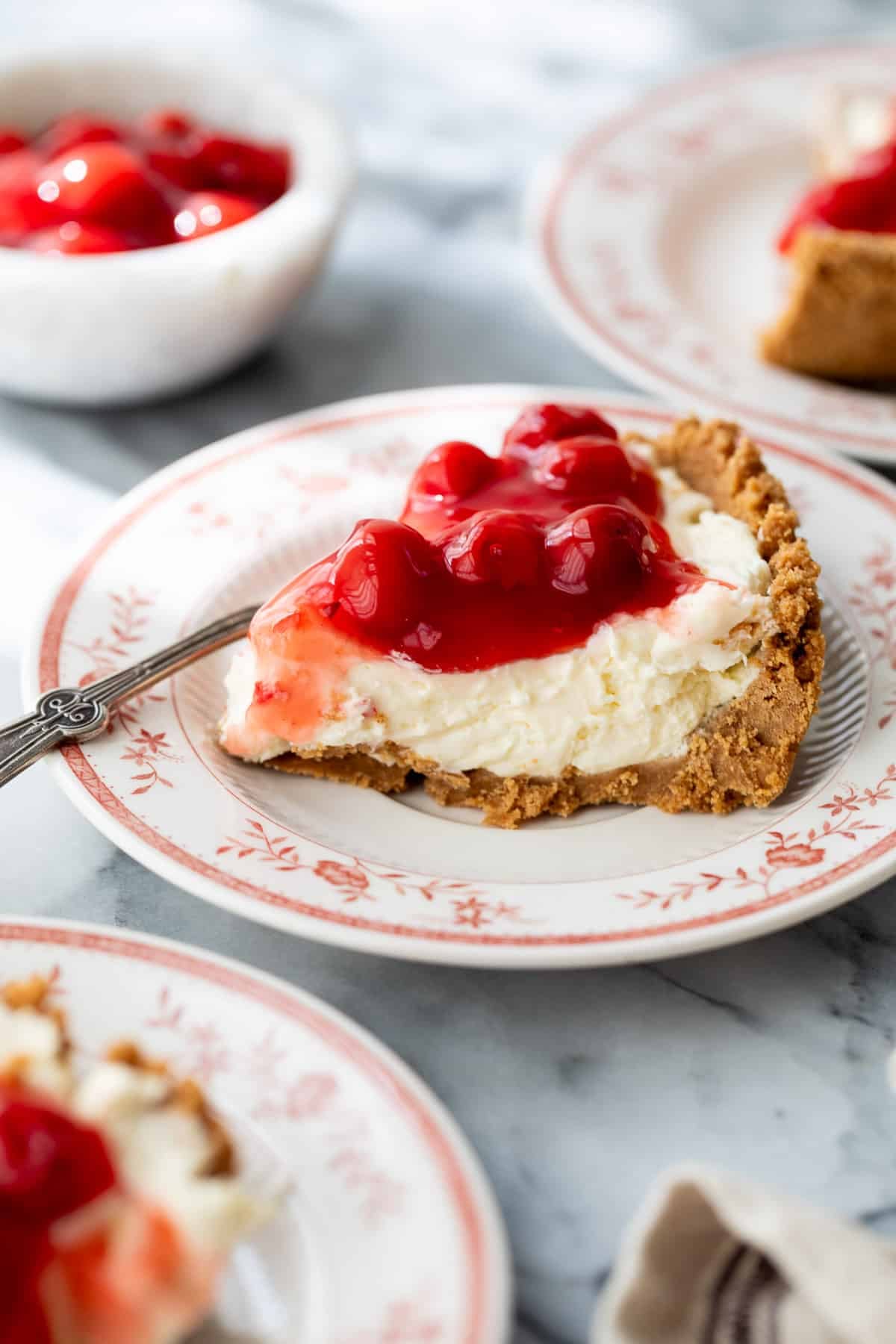 a slice of cheesecake on a plate topped with cherries