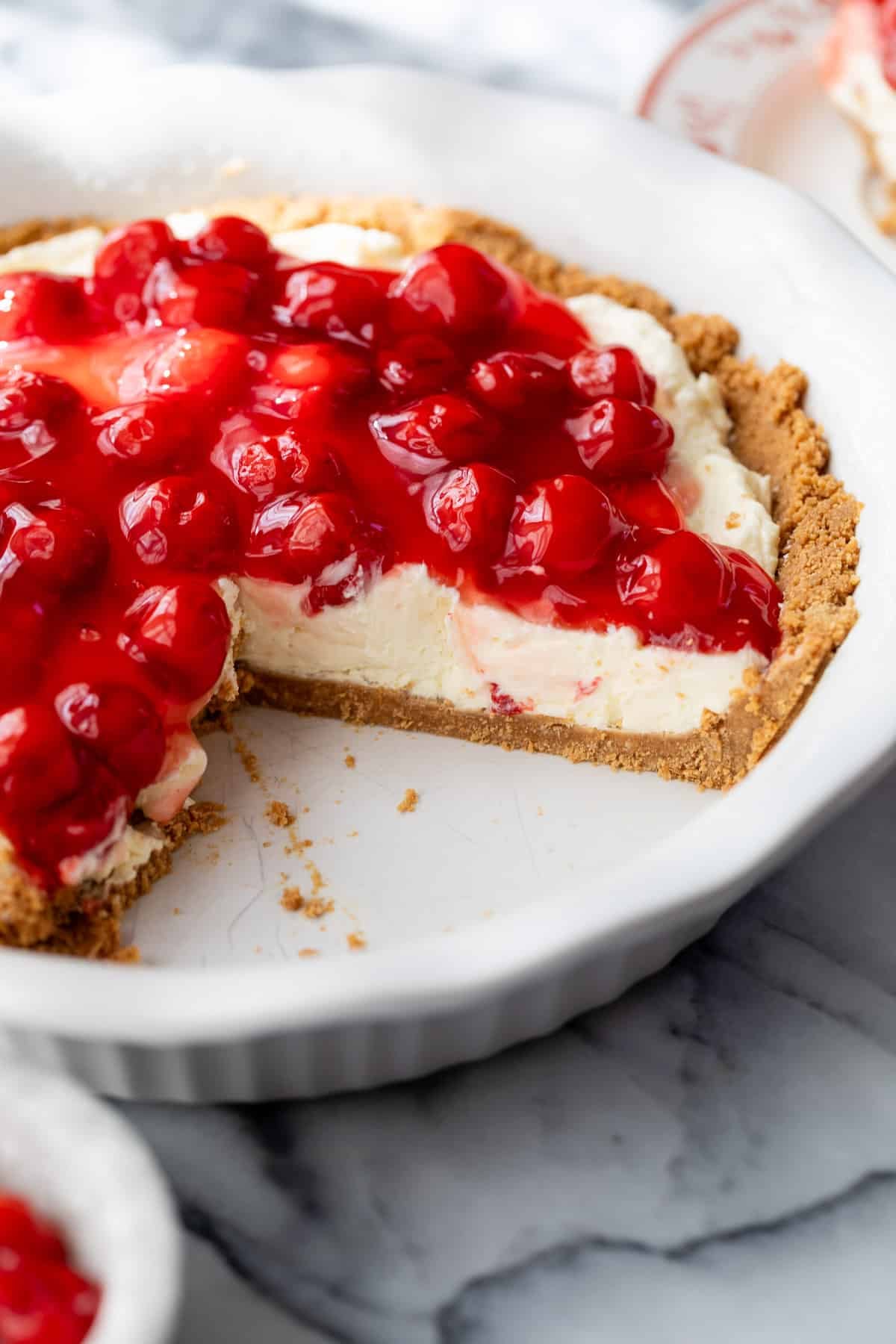 a whole pie topped with cherries with a slice taken out of it