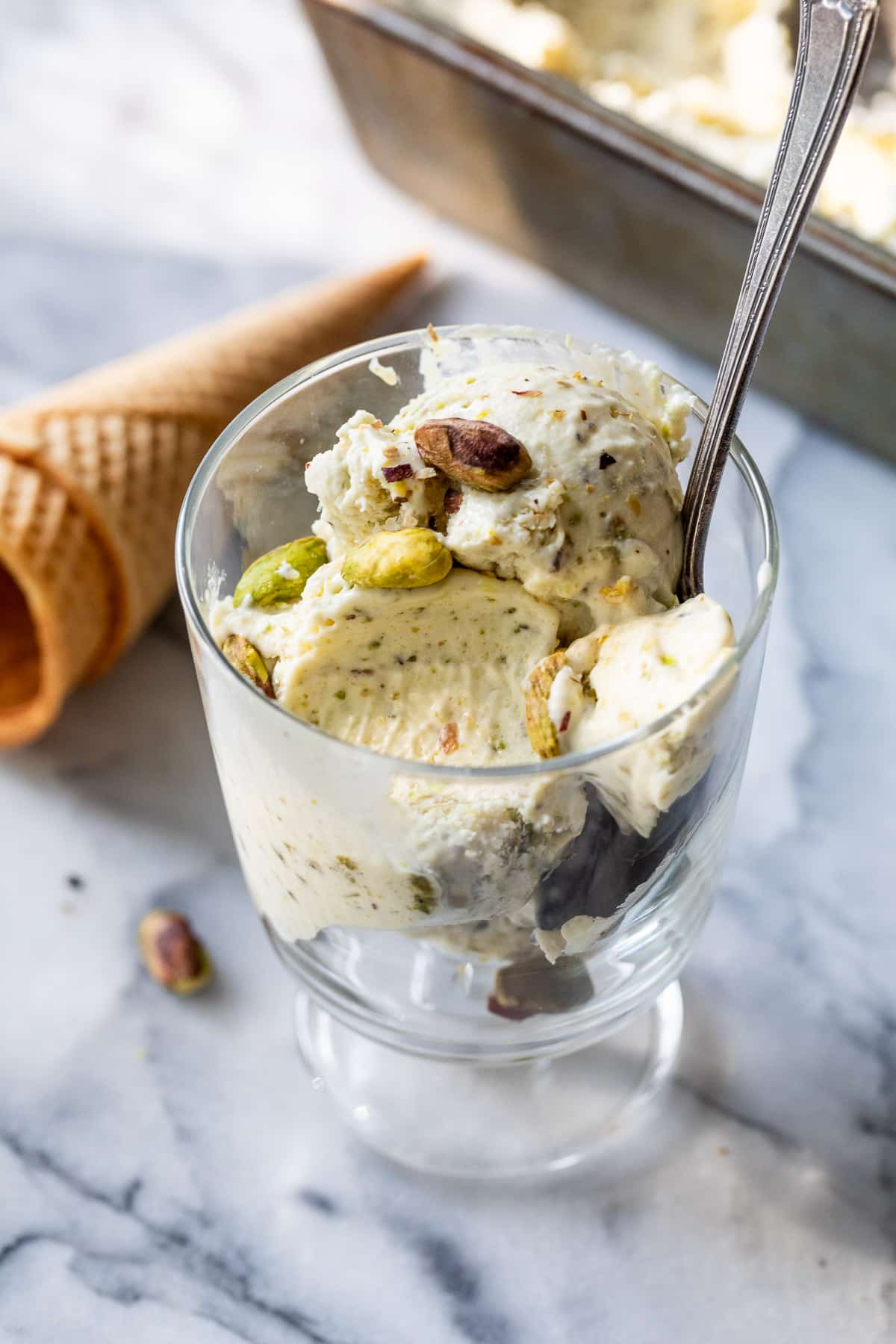 using a spoon to eat No Churn Pistachio Ice Cream from a glass.