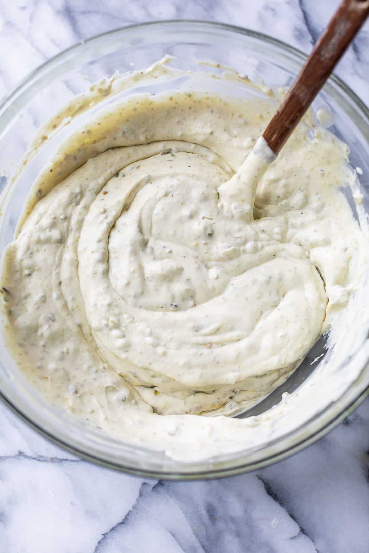 folding the liquid mixture for No Churn Pistachio Ice Cream with a spatula in a large glass bowl.