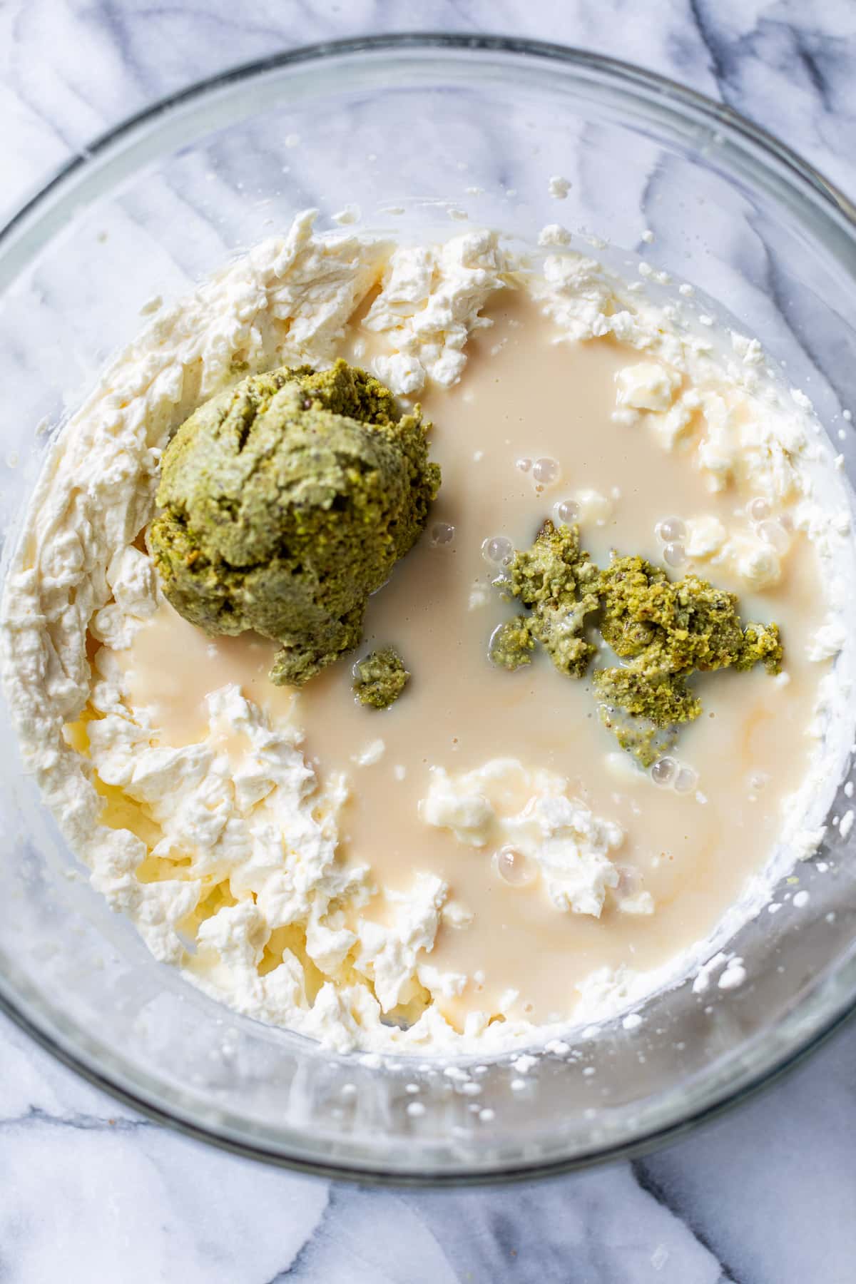 whipped cream, milk, and pistachio butter in a large glass bowl.