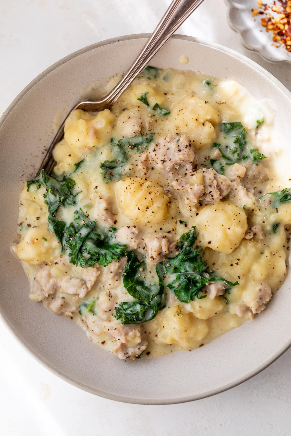 overhead view of Gnocchi with Sausage and Kale and a fork in a bowl.