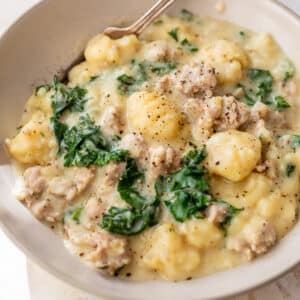 side view of Gnocchi with Sausage and Kale and a fork in a bowl.