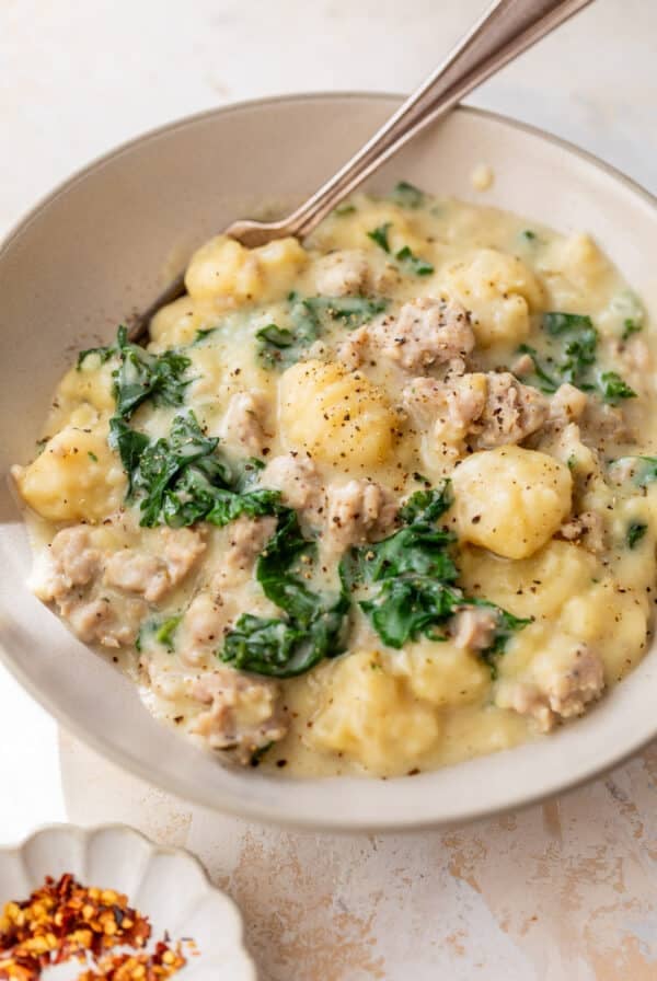 side view of Gnocchi with Sausage and Kale and a fork in a bowl.