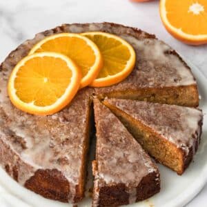 side view of a sliced orange cake on a white plate.