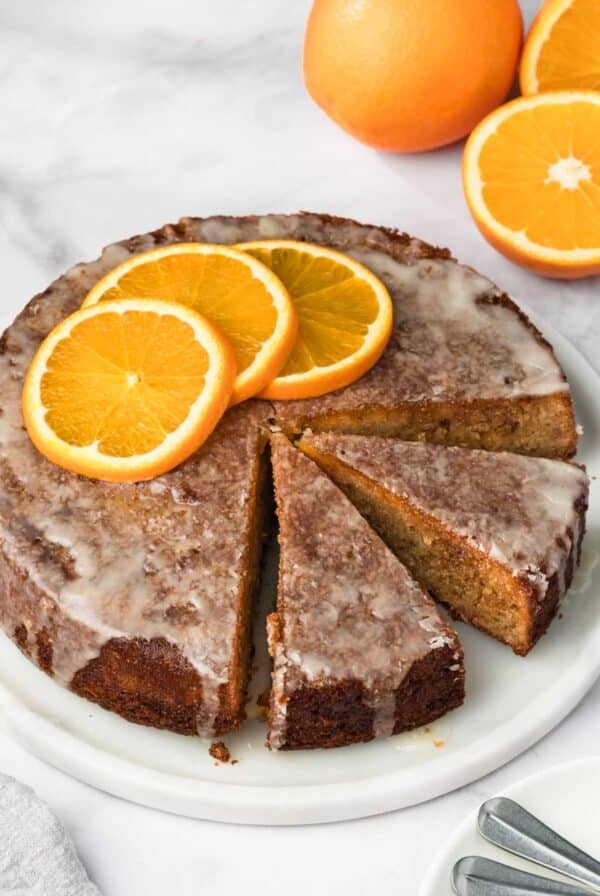 side view of a sliced orange cake on a white plate.