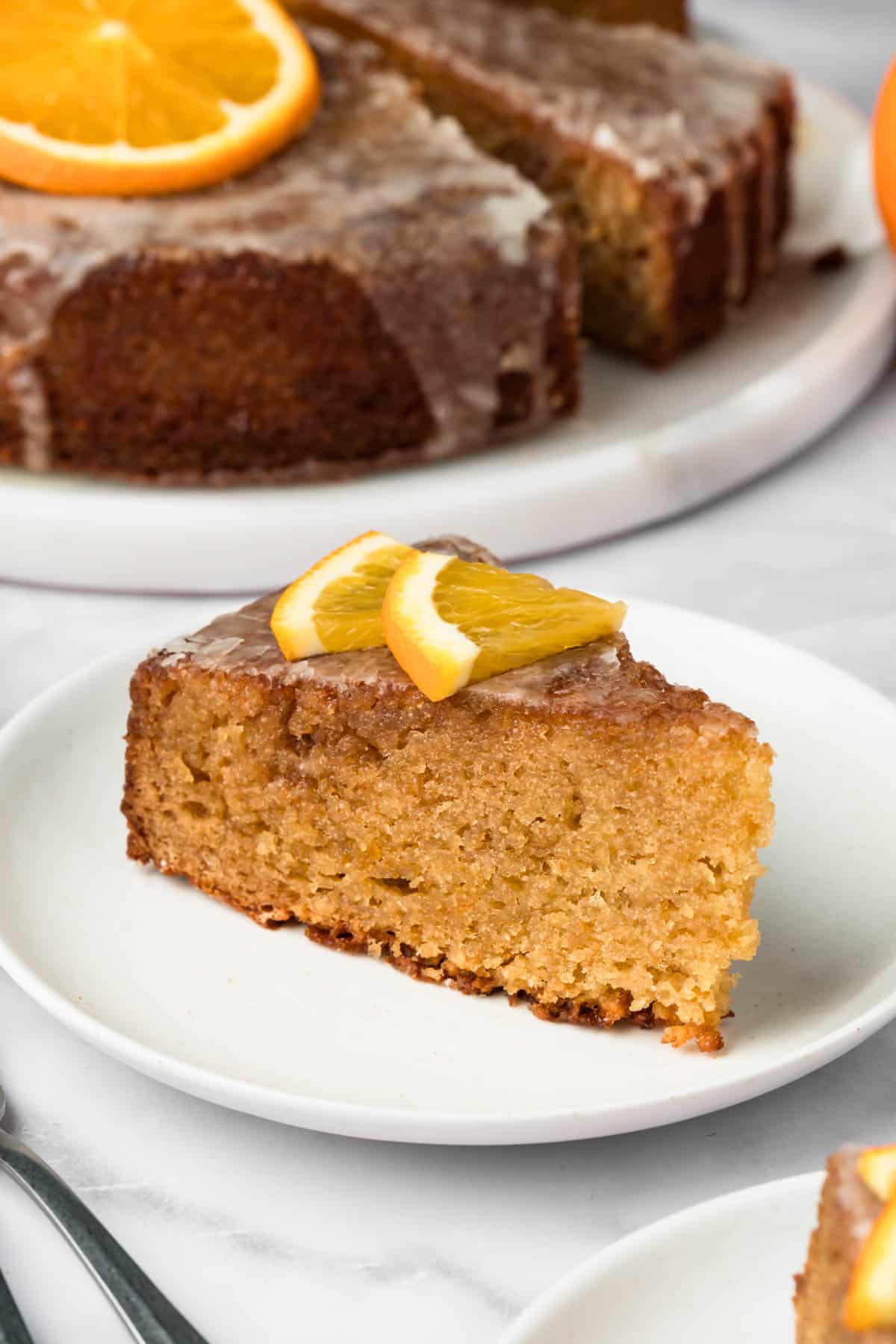 close up on a slice of orange cake on a white plate.