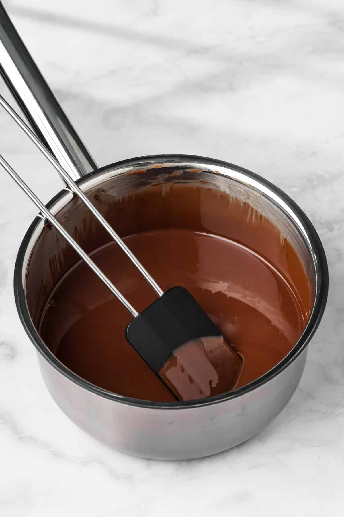 a black spatula in a saucepan filled with melted chocolate for paleo brownies.